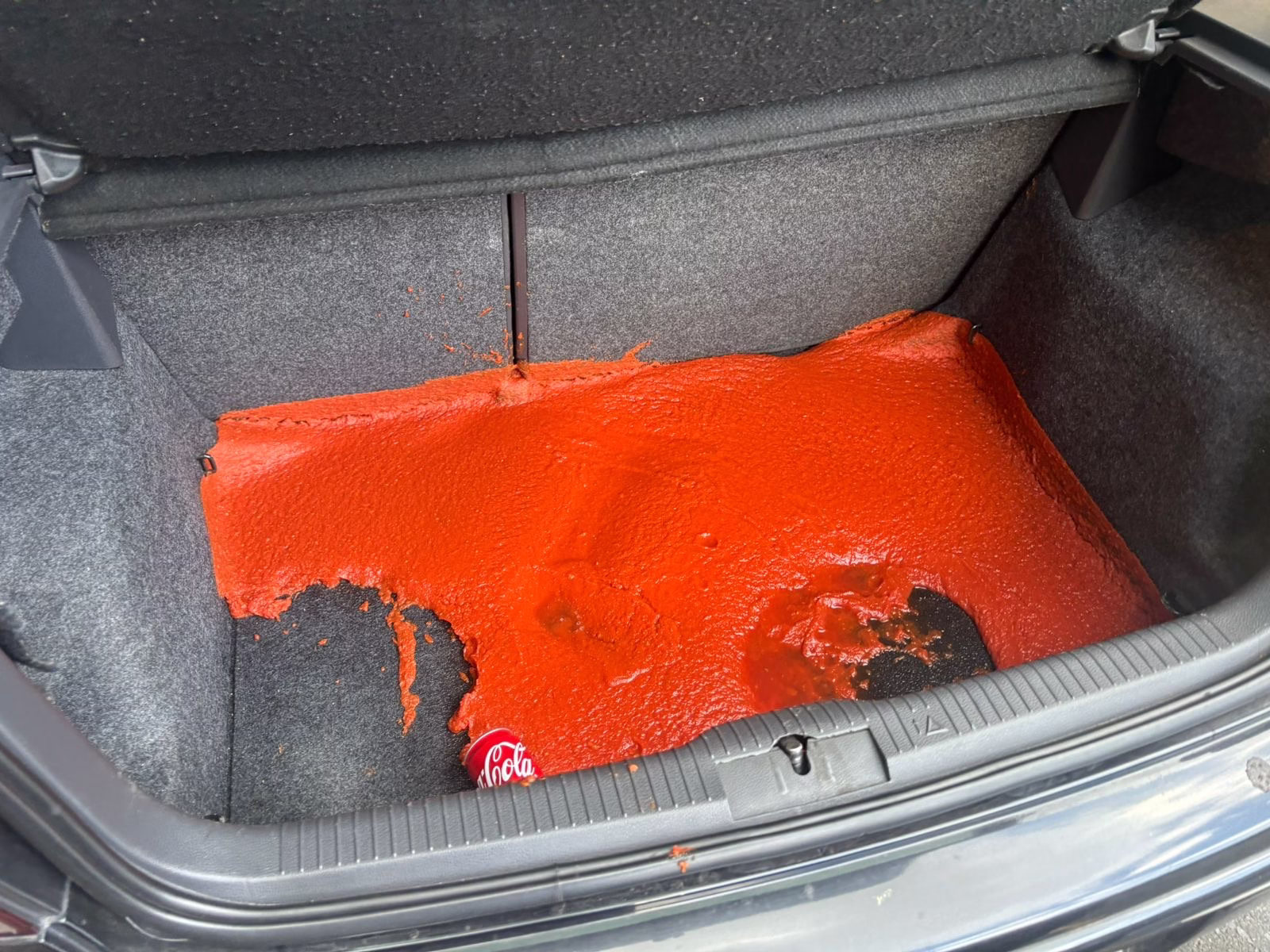 A pot of tomato sauce for pizza that fell out in the boot of a car